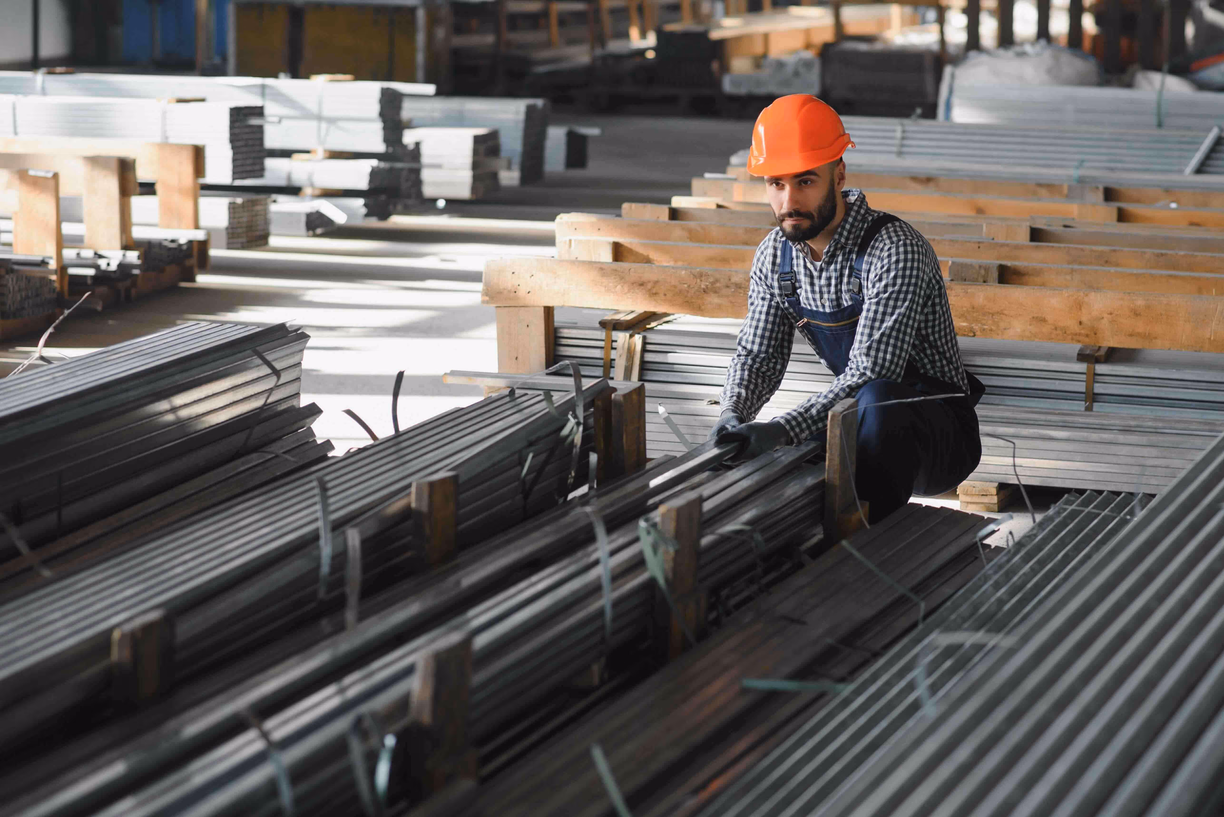 Contractor in hard hat measuring steel materials on a job site to track job costs and material quantities